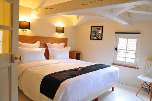 a bedroom with a large bed with white sheets and a window at Les Glycines Vézelay in Vézelay