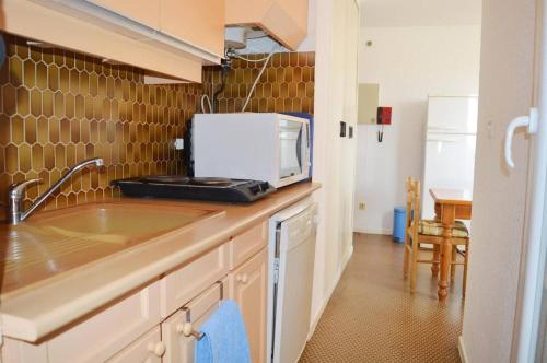 une cuisine avec un évier et un micro-ondes sur un comptoir dans l'établissement Appart 2 pièces 4 couchages ARGELES SUR MER AR450-0912, à Argelès-sur-Mer