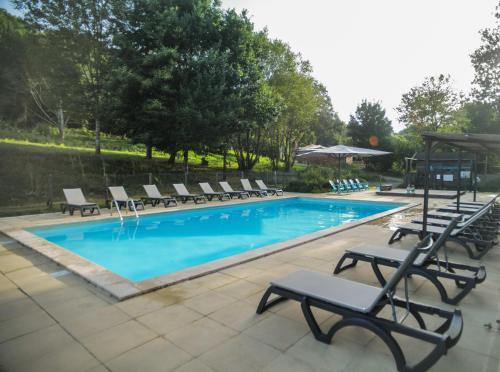 une piscine avec des chaises longues et une piscine dans l'établissement Camping Domaine le Peyral - Le Papillon Lodge, à La Salvetat-sur-Agout