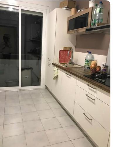 une cuisine avec des armoires blanches et un micro-ondes dans l'établissement nice appartement, montpellier center 3 rooms, à Montpellier