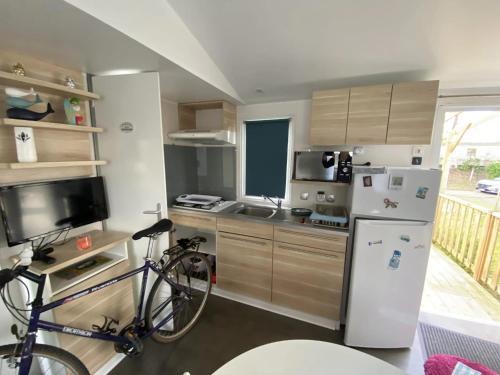 a kitchen with a bicycle and a refrigerator at La CABANE d'Arthur in Camiers