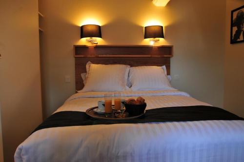 a bed with a tray with two cups and two drinks at Les Glycines Vézelay in Vézelay