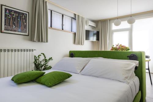 a green and white bed with two green pillows on it at Halloggio98 in Rivalta