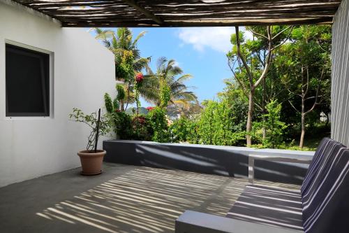 a porch with a chair and a tv and trees at Casa das Palmeiras - Palm Tree House in Ponta do Ouro