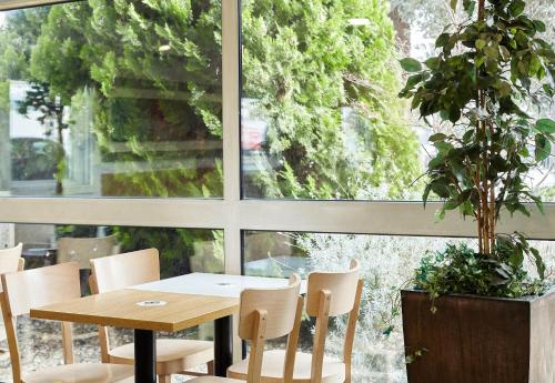 a table and chairs in a room with a window at B&B HOTEL Orly Chevilly-Larue - Nationale 7 in Chevilly-Larue