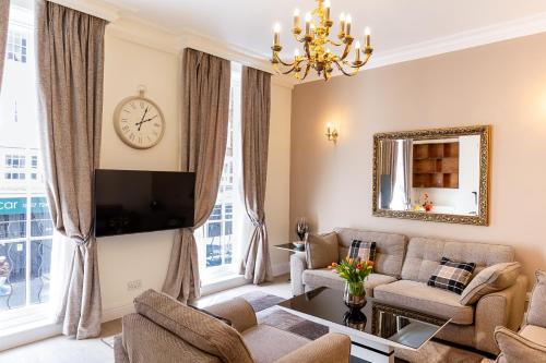 a living room with a couch and a clock on the wall at Marylebone Executive Apartments in London