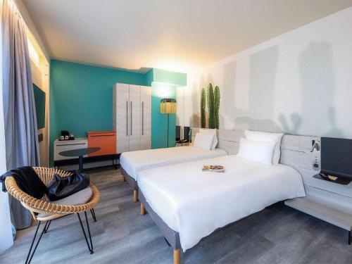 a hotel room with two beds and a tv at Novotel Monte-Carlo in Monte Carlo