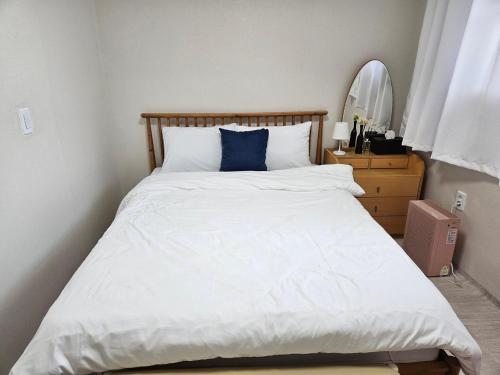 a bedroom with a white bed with a blue pillow at Tov Stay Atti in Pyeongtaek