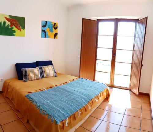 a bedroom with a bed with a blue blanket on it at Alqueva Beach House in Mourão