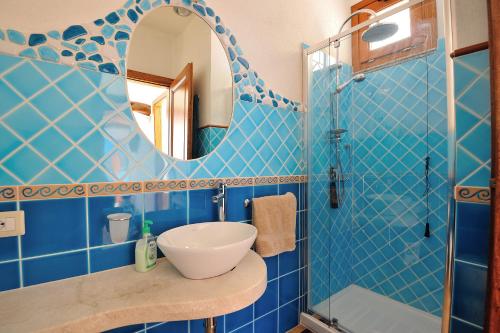 bagno piastrellato blu con lavandino e specchio di Villa Maddalena a Baunei