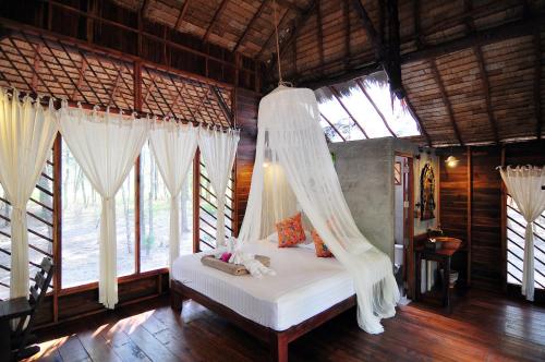 a bedroom with a bed with a mosquito net at The Moken Eco Village - SHA plus in Ko Phra Thong