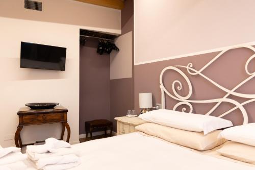 a bedroom with a white bed and a flat screen tv at Ca' Baetti l'Antica Corte in Roncola