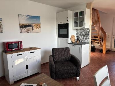 a living room with a chair and a microwave at Strandhaus in der Düne in Dierhagen
