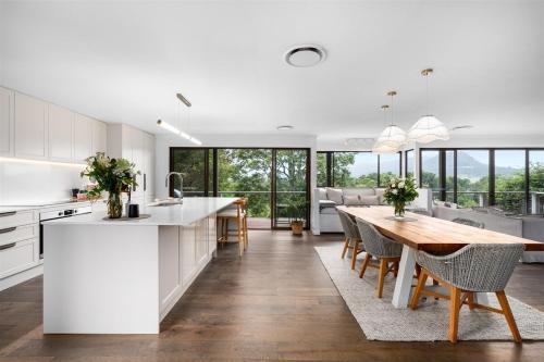 a kitchen and dining room with white cabinets and a wooden table at Calla Vale - 3 Bed House Incredible Valley Views in Kangaroo Valley
