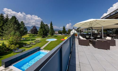 a balcony with a swimming pool and a patio at Hotel-Restaurant Grimmingblick in Bad Mitterndorf