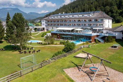 a hotel with a soccer field and a building at Hotel-Restaurant Grimmingblick in Bad Mitterndorf
