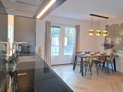 a kitchen and dining room with a table and chairs at Luxe wellnesshuis Drenthe met sauna, whirlpool en omheinde tuin VP048 in Hoogersmilde