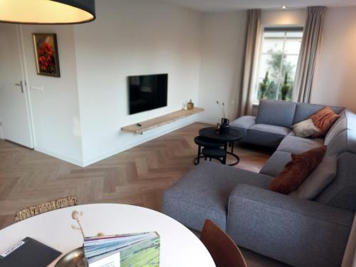 a living room with a couch and a table at Luxe wellnesshuis Drenthe met sauna, whirlpool en omheinde tuin VP048 in Hoogersmilde