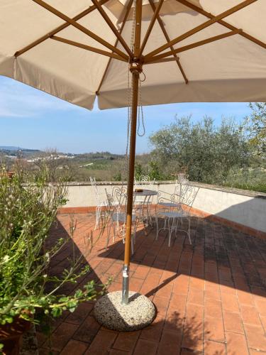 an umbrella on a patio with a table and chairs at CasaLeTolfe Residence in Siena