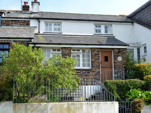 ein Backsteinhaus mit einem Zaun davor in der Unterkunft Watercolour Cottage in Lerryn