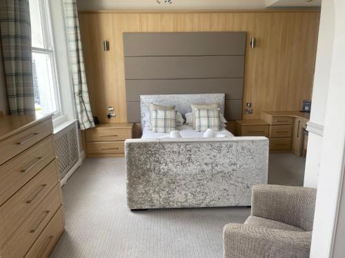 a large bedroom with a bed and a chair at The Wildings Hotel & Tudno's Restaurant in Llandudno