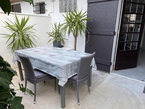 une table et des chaises dans un patio orné de plantes dans l'établissement Studio lumineux avec terrasse, à Arcachon
