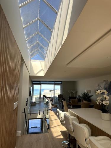 a living room with a skylight and a table and chairs at Elegant Beach front Villa in Bloubergstrand