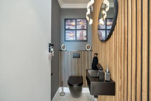 a bathroom with a black toilet and a mirror at Elegant Beach front Villa in Bloubergstrand