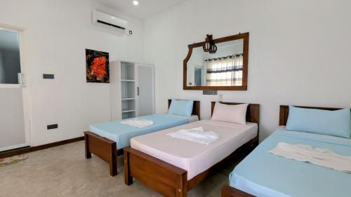 two beds in a room with a mirror at Skyy Villa matara in Matara