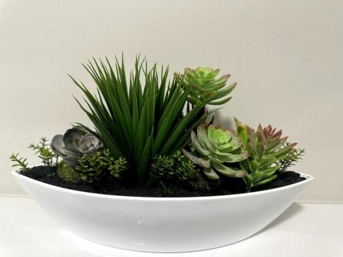 a white bowl filled with plants on a table at Elegant Beach front Villa in Bloubergstrand