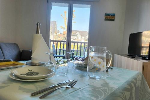 une table avec une assiette et des verres sur une table dans l'établissement Nice T2 with balcony - near beach, à Cabourg