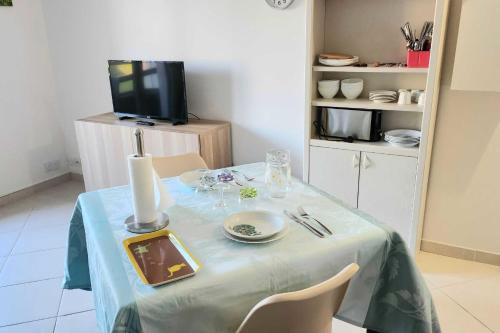 une table à manger avec un chiffon bleu et une télévision dans l'établissement Nice T2 with balcony - near beach, à Cabourg