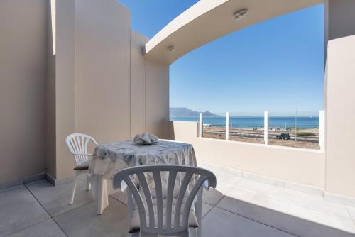 a dining room with a table and chairs and a view of the ocean at Elegant Beach front Villa in Bloubergstrand
