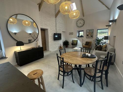 a living room with a table and chairs and a mirror at Beudy at Pentrecelyn - a gorgeous barn conversion with hot tub in Carmarthen