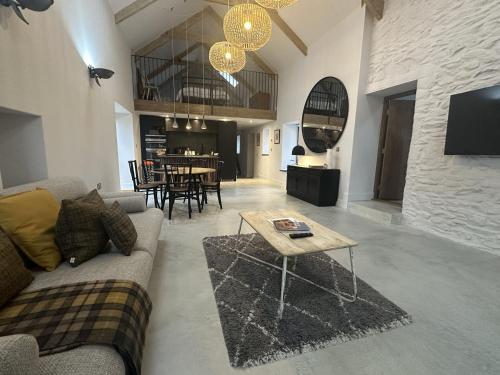 a living room with a couch and a table at Beudy at Pentrecelyn - a gorgeous barn conversion with hot tub in Carmarthen