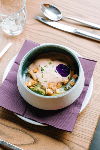a bowl of soup sitting on a table with a napkin at Les Violettes Hotel & Spa in Jungholtz