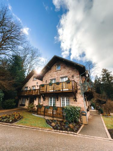 a large brick building with a balcony on the front at Les Violettes Hotel & Spa in Jungholtz
