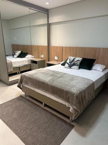 a bedroom with a large bed and a mirror at Apto Cancún Foz in Foz do Iguaçu