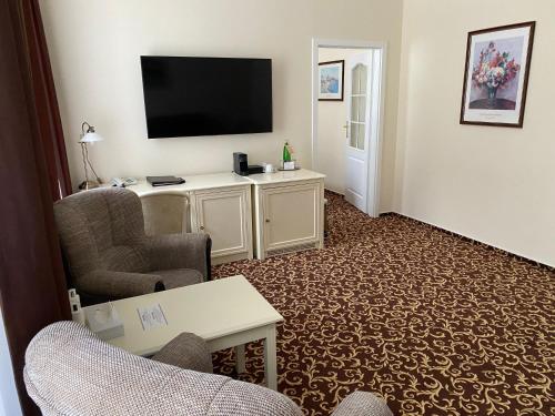 a living room with a flat screen tv and chairs at Reitenberger Spa Medical in Mariánské Lázně