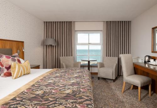 a hotel room with a bed and a table and chairs at Ballygally Castle in Larne