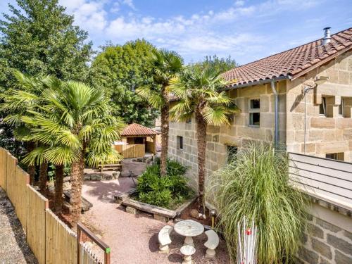 une cour arrière avec des palmiers et un bâtiment dans l'établissement Au Petit Grammont - Magnifique batisse - 2 gites, à Lacapelle-Marival