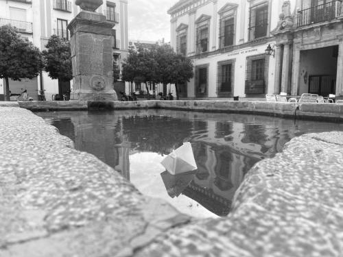 a white paper boat in a puddle of water at Las Fadrique in Córdoba