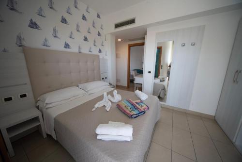 a bedroom with two beds with towels and a mirror at Hotel ABC in Riccione