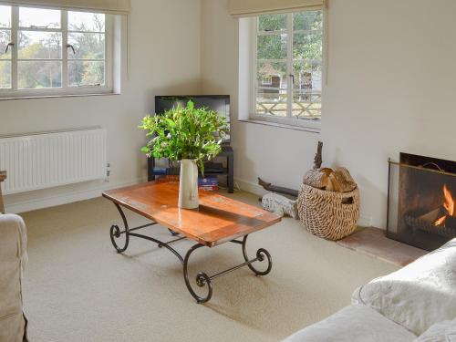 a living room with a table and a fireplace at Brookside Cottage in Burley