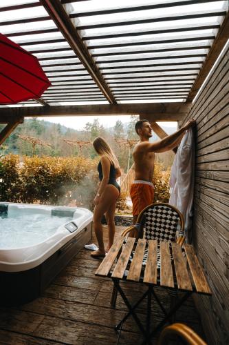 a man and a woman standing next to a bath tub at Les Violettes Hotel & Spa in Jungholtz