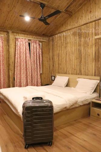 a bed with a suitcase in a room at Tarapith Tapabon Eco Resort in Tarapith