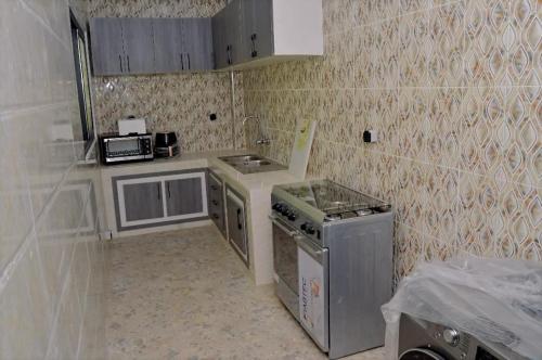 a small kitchen with a stove and a microwave at Résidence CHEZ TIMERA in Keur Massar