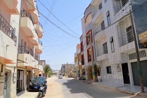 a motorcycle parked on the side of a street with buildings at Résidence CHEZ TIMERA in Keur Massar