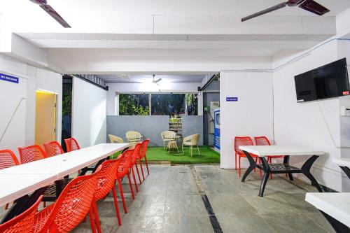 a room with red chairs and tables and a flat screen tv at FabHotel The Botanica- Nr Hmwssb Kondapur section office-Masjid Banda, Kondapur in Kondapur