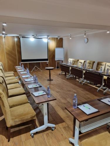 a conference room with tables and chairs and a screen at Plaza Hotel Almaty in Almaty